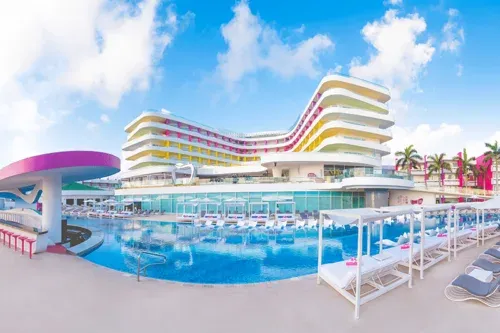 Curved white resort building behind the pool at Temptation Cancun Resort